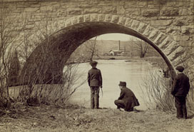 two men under bridge near water