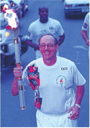 jim boeheim carrying the olympic torch through syracuse in june 1996
